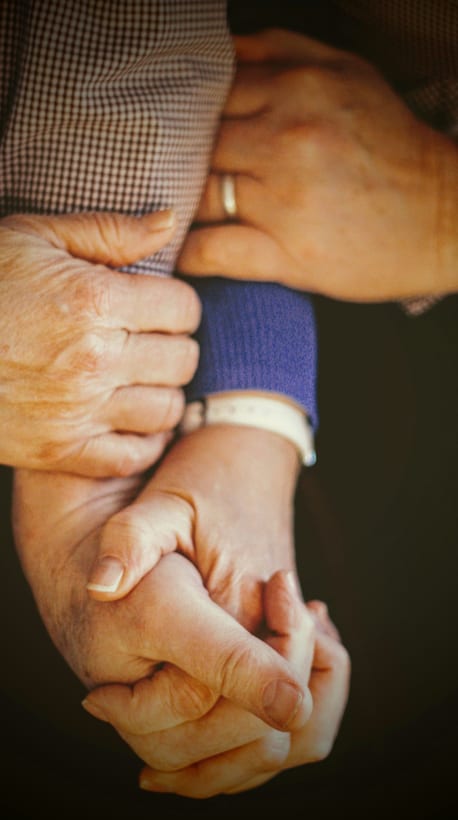 A caregiver's hands supporting a senior's arm
