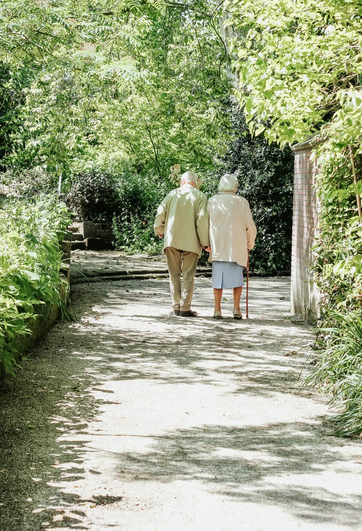 A senior couple walking together along a shaded path