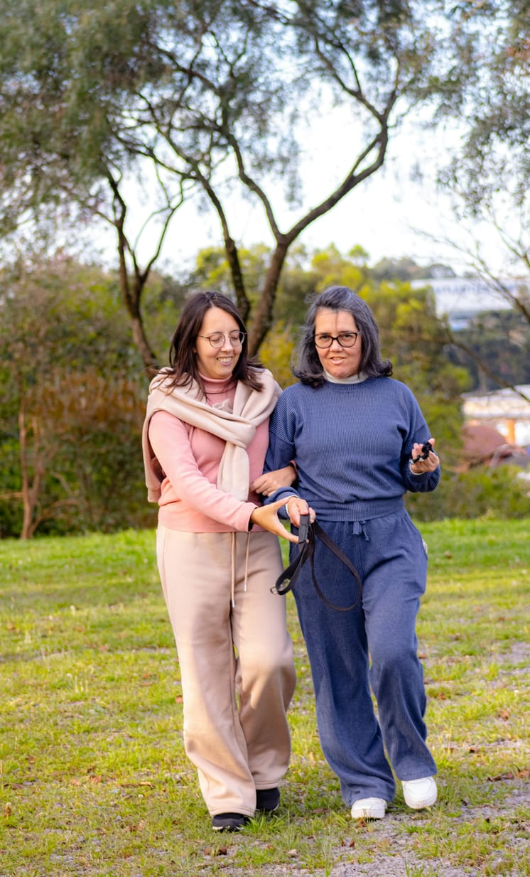 A caregiver walking arm in arm with a senior client outdoors