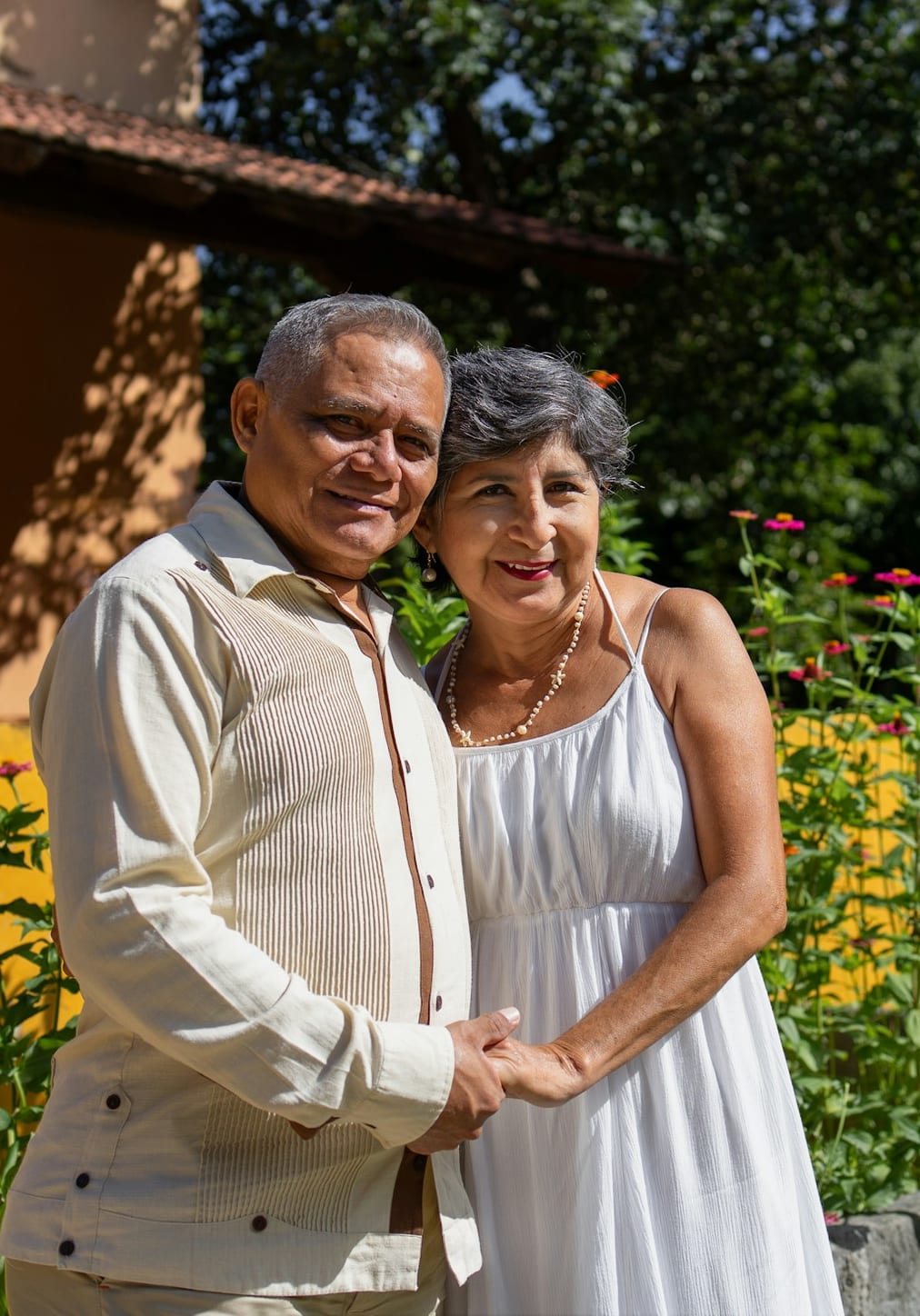 A senior couple standing together outside their home