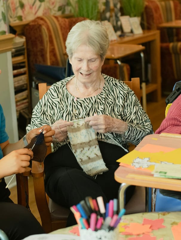 A senior working on a craft project with her caregiver alongside her