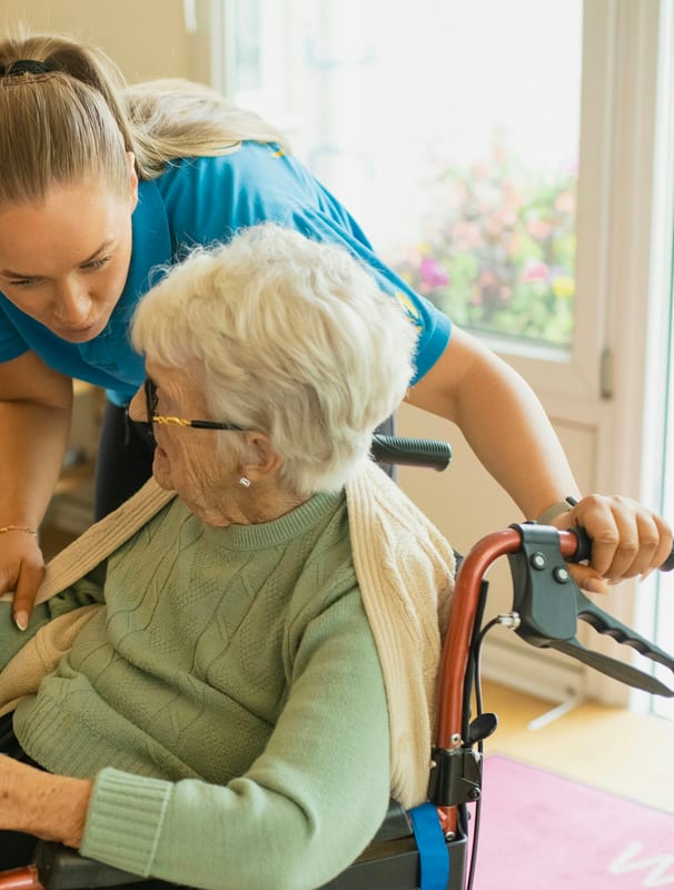 A caregiver helping a senior woman steady herself at home